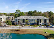 Thumbnail 22 of 39 - A large apartment complex with a pond in front.
