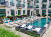 Thumbnail 26 of 41 - an outdoor pool with lounge chairs and umbrellas in front of an apartment building