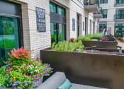 Thumbnail 39 of 41 - a seating area with a bench and flowers in front of a building