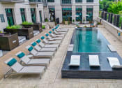 Thumbnail 30 of 41 - a pool with lounge chairs and a building in the background