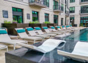Thumbnail 29 of 41 - a pool with lounge chairs and a building in the background
