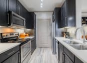 Thumbnail 18 of 33 - a kitchen with black cabinets and white counter tops and a sink