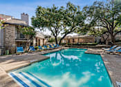 Thumbnail 21 of 22 - A swimming pool surrounded by trees and chairs.