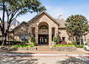 Thumbnail 16 of 22 - A building with a stone facade and a sign that reads "Ladies' Manor" is surrounded by trees and flowers.