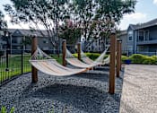 Thumbnail 64 of 68 - A hammock is strung between two wooden posts in a gravel area.