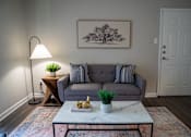 Thumbnail 48 of 68 - A living room with a grey couch, a white coffee table, and a painting on the wall.
