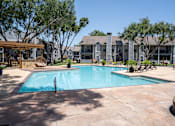 Thumbnail 51 of 68 - A large swimming pool surrounded by a patio and trees.