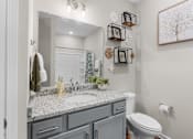 Thumbnail 8 of 26 - A bathroom with a toilet, sink, and mirror.