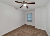 Thumbnail 13 of 23 - a bedroom with white walls and a ceiling fan