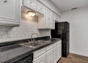Thumbnail 9 of 23 - a kitchen with white cabinets and black appliances