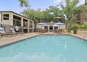 Thumbnail 42 of 44 - a swimming pool with lounge chairs and umbrellas in front of a building