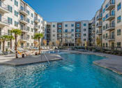 Thumbnail 29 of 32 - A swimming pool in front of apartment buildings.