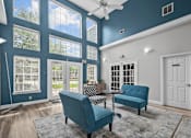 Thumbnail 21 of 26 - A blue chair and a blue sofa are in a room with a ceiling fan.
