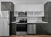 Thumbnail 16 of 42 - A modern kitchen with a refrigerator, oven, microwave, and sink.