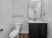 Thumbnail 5 of 42 - A bathroom with a toilet, sink, and mirror.