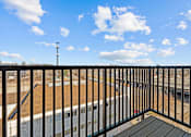 Thumbnail 22 of 42 - A balcony with a black railing and a view of a train track and a building.