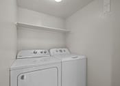 Thumbnail 12 of 26 - Two white washing machines in a small laundry room.