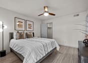 Thumbnail 9 of 26 - A bedroom with a bed, a ceiling fan, and two picture frames on the wall.
