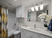 Thumbnail 11 of 26 - A bathroom with a white toilet, sink, and a mirror.