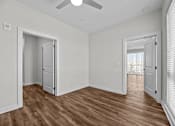 Thumbnail 25 of 42 - A room with a ceiling fan and wooden flooring.