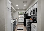 Thumbnail 1 of 26 - A modern kitchen with black appliances and white cabinets.
