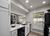 Thumbnail 2 of 26 - A modern kitchen with white cabinets and a black refrigerator.