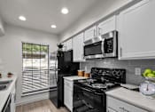Thumbnail 3 of 26 - A modern kitchen with a black refrigerator, stove, and microwave.