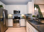 Thumbnail 1 of 28 - A modern kitchen with stainless steel appliances and white cabinets.