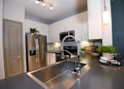 Thumbnail 2 of 28 - A modern kitchen with a stainless steel sink and refrigerator.