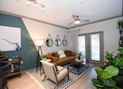 Thumbnail 4 of 28 - A living room with a brown couch, a black floor lamp, and a painting on the wall.