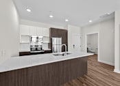 Thumbnail 29 of 42 - A modern kitchen with a white countertop and wooden cabinets.