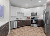 Thumbnail 18 of 39 - A modern kitchen with wooden floors and stainless steel appliances.