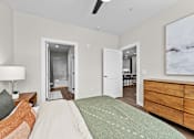 Thumbnail 9 of 39 - A bedroom with a bed, dresser, and painting on the wall.