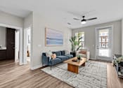 Thumbnail 6 of 39 - A living room with a blue couch and a painting on the wall.