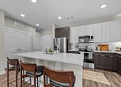 Thumbnail 4 of 39 - A kitchen with a white island and brown chairs.