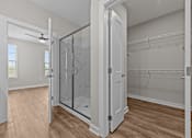 Thumbnail 35 of 39 - A walk-in closet with a glass door and wooden floors.