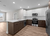 Thumbnail 31 of 39 - A modern kitchen with wooden floors and white countertops.