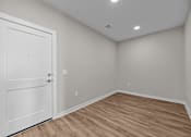 Thumbnail 36 of 39 - A room with a white door and wooden floor.