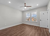 Thumbnail 18 of 37 - A room with a ceiling fan and wooden flooring.