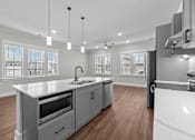 Thumbnail 14 of 37 - A modern kitchen with a white countertop and wooden flooring.