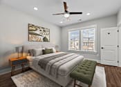 Thumbnail 4 of 37 - A bedroom with a large bed, a green ottoman, and a ceiling fan.