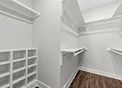 Thumbnail 7 of 37 - A white walk-in closet with shelves and a wooden floor.