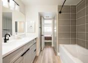 Thumbnail 33 of 33 - A bathroom with a white tub and a white sink.