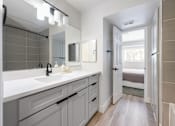 Thumbnail 17 of 33 - A bathroom with a sink, mirror, and a door leading to a bedroom.