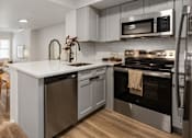 Thumbnail 12 of 33 - A modern kitchen with a stainless steel oven and a wooden floor.