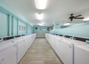 Thumbnail 10 of 27 - a laundry room with white washers and dryers and blue walls