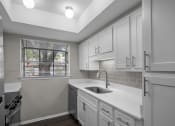 Thumbnail 10 of 21 - an empty kitchen with white cabinets and a window