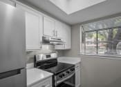 Thumbnail 11 of 21 - an empty kitchen with white cabinets and a window