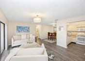 Thumbnail 10 of 27 - a living room with white couches and chairs and a kitchen in the background