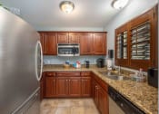 Thumbnail 17 of 46 - a kitchen with wooden cabinets and granite countertops
